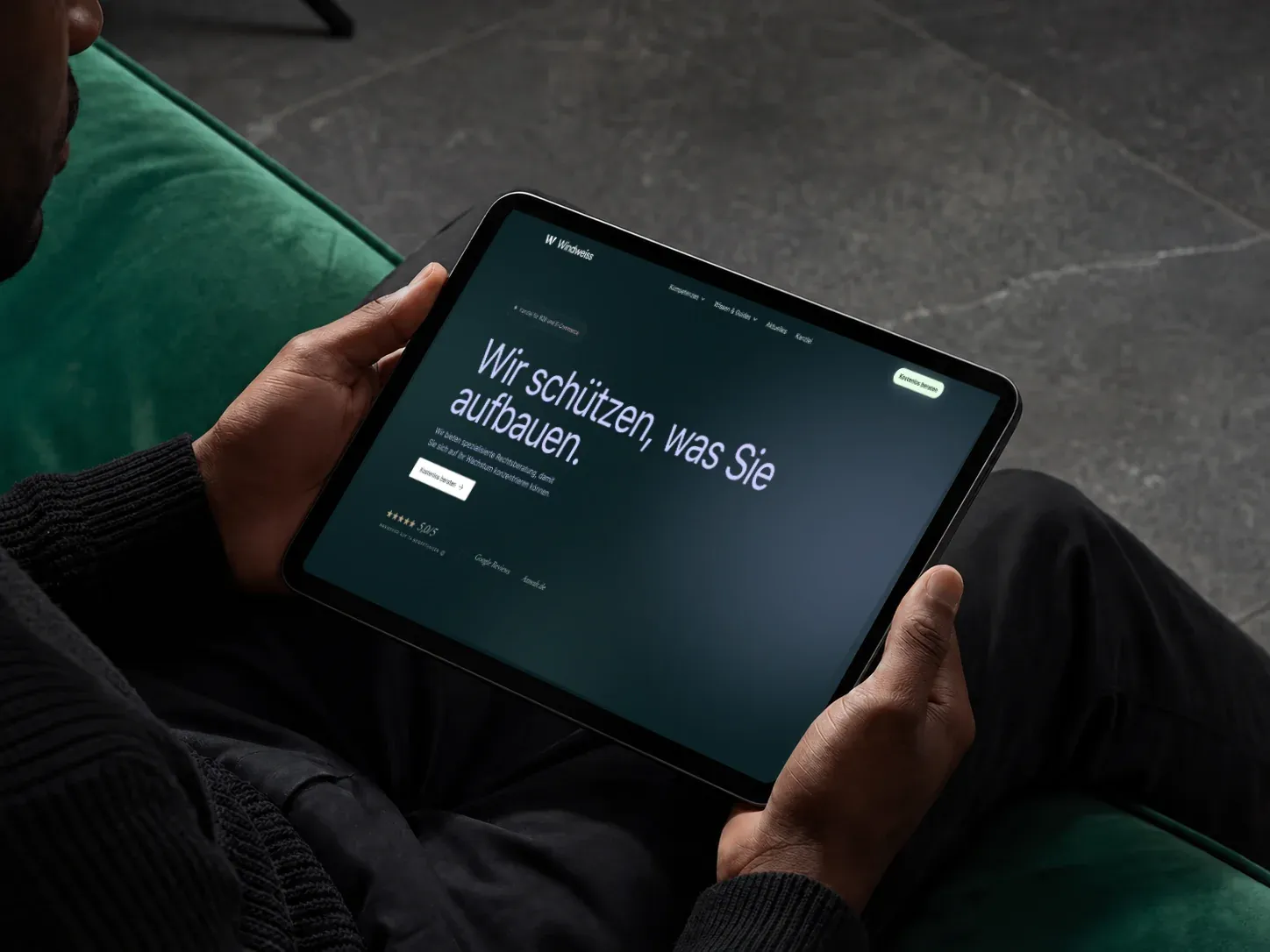 Person hält ein Tablet mit der Windweiss-Website in einer dunklen Gestaltung